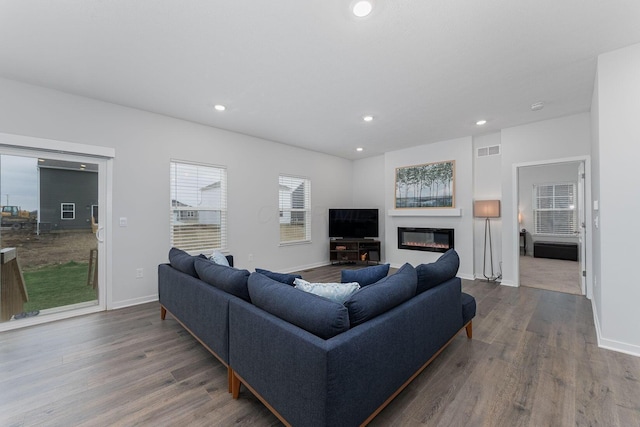 living room featuring recessed lighting, a glass covered fireplace, and wood finished floors
