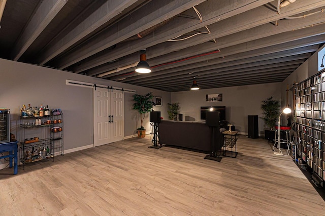 interior space featuring baseboards, a barn door, and wood finished floors