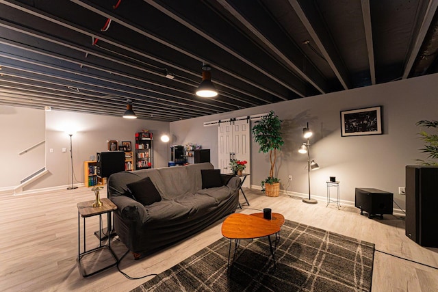 living room featuring a barn door, baseboards, and wood finished floors