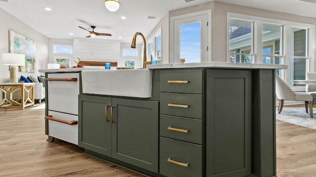 interior space with open floor plan, green cabinetry, recessed lighting, and a sink