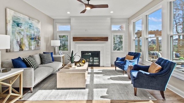 living room featuring a ceiling fan, wood finished floors, a fireplace, baseboards, and recessed lighting