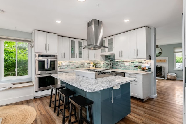 3588 Reed Rd Unit 4, Columbus, OH 43221 - kitchen featuring island range hood, stainless steel double oven, tasteful backsplash, a kitchen island, and a breakfast bar area