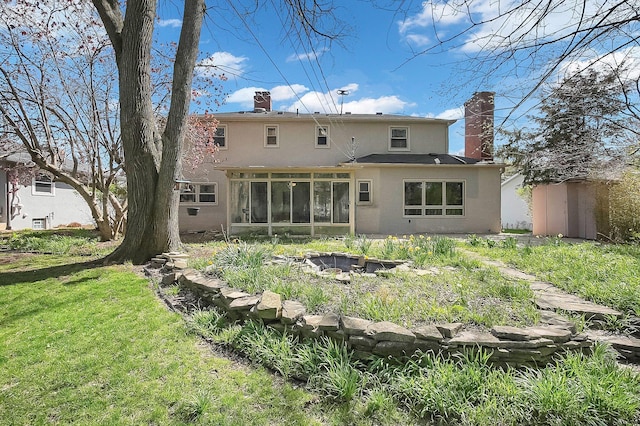 back of house with a yard, a sunroom, stucco siding, and a chimney
