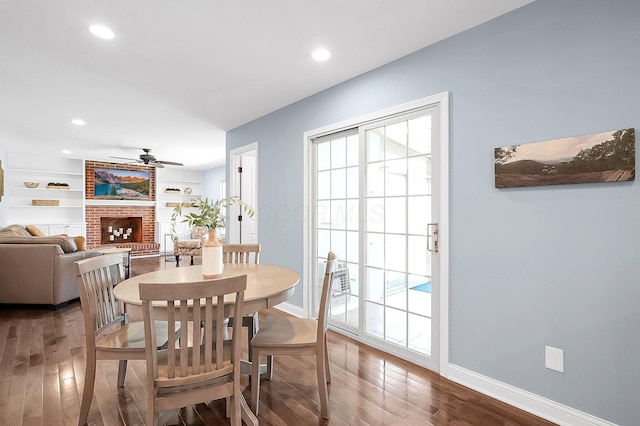 dining space with a fireplace, a ceiling fan, recessed lighting, wood finished floors, and baseboards