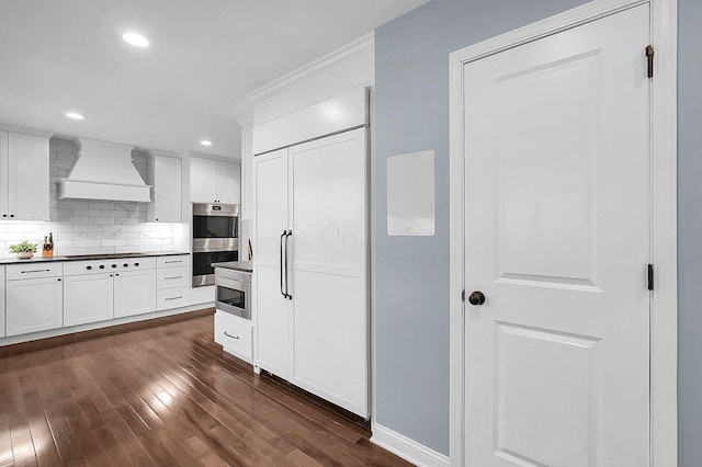 kitchen with custom exhaust hood, dark wood-style floors, stainless steel double oven, paneled built in fridge, and cooktop