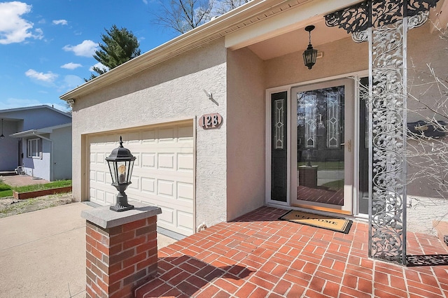 property entrance with a garage, driveway, and stucco siding