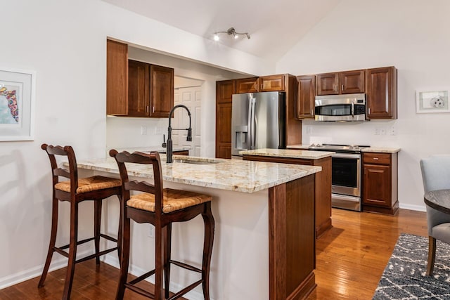 4889 Ashleigh Dr, Dublin, OH 43016 - kitchen with a breakfast bar, light stone counters, a sink, stainless steel appliances, and dark wood-style floors