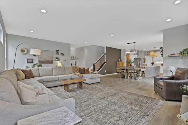 living area with baseboards, recessed lighting, light wood-style floors, and stairs