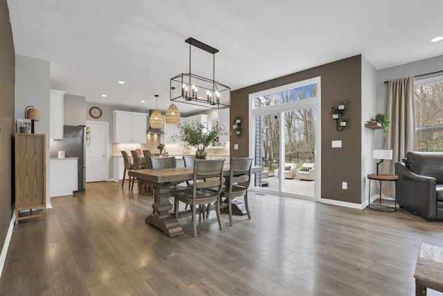 dining space featuring dark wood-style flooring, baseboards, an inviting chandelier, and recessed lighting