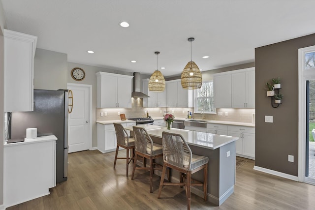 kitchen with stainless steel appliances, a center island, wall chimney exhaust hood, and wood finished floors