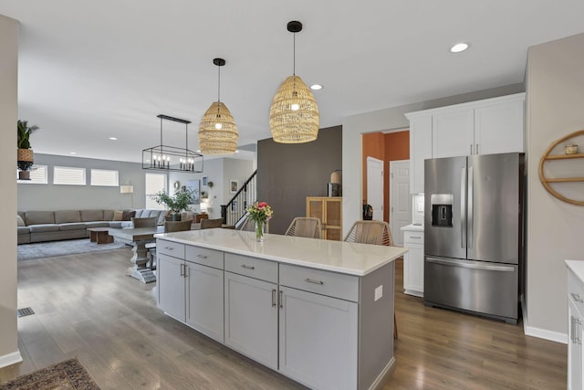 kitchen featuring gray cabinets, light countertops, stainless steel refrigerator with ice dispenser, dark wood finished floors, and pendant lighting