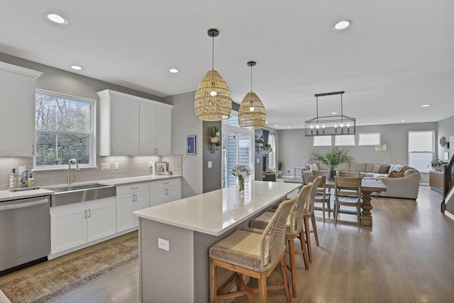 kitchen featuring tasteful backsplash, open floor plan, a breakfast bar area, stainless steel dishwasher, and a sink