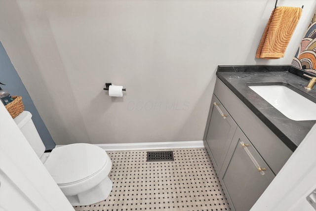 bathroom with toilet, vanity, baseboards, and visible vents