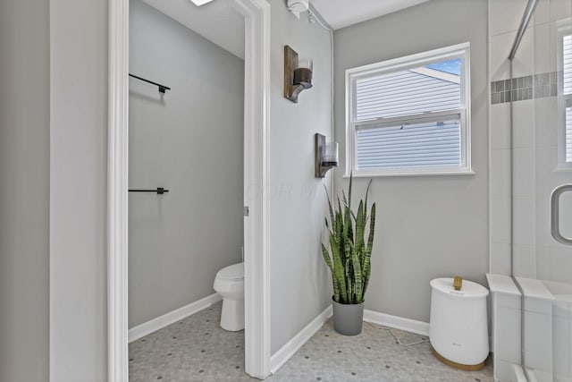 bathroom with a stall shower, baseboards, and toilet