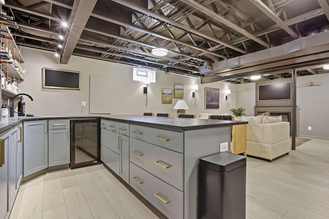 kitchen featuring gray cabinets, a sink, dark countertops, and beverage cooler