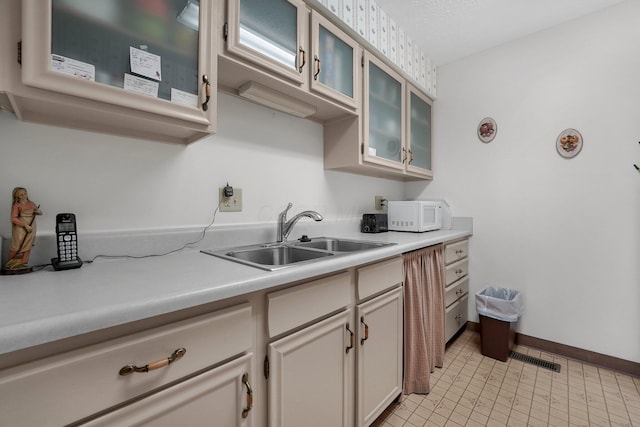 6346 Well Fleet Dr Unit 96, Columbus, OH 43231 - kitchen with glass insert cabinets, visible vents, a sink, light countertops, and white microwave