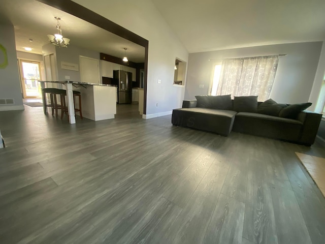 living room featuring visible vents, baseboards, vaulted ceiling, and dark wood finished floors