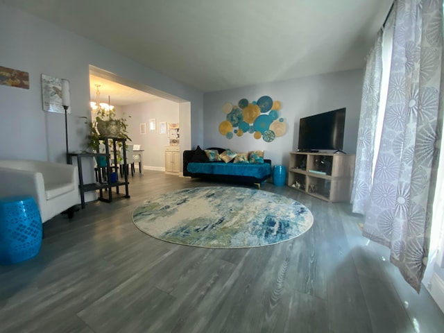 living area with baseboards, a notable chandelier, and wood finished floors