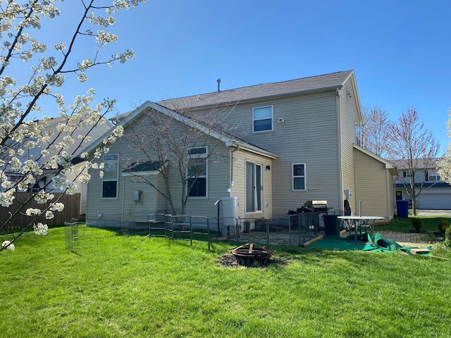 rear view of property featuring an outdoor fire pit, a yard, and fence