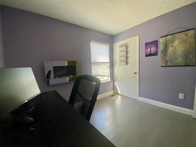 office featuring a textured ceiling, wood finished floors, and baseboards