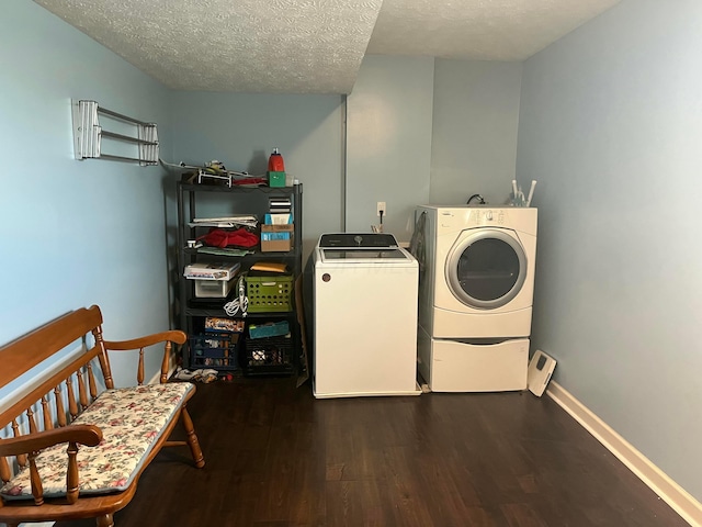 washroom featuring laundry area, a textured ceiling, separate washer and dryer, wood finished floors, and baseboards