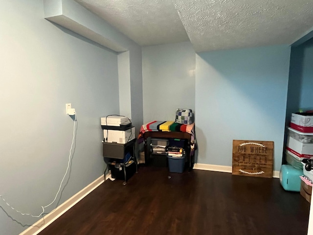 misc room featuring a textured ceiling, baseboards, and wood finished floors