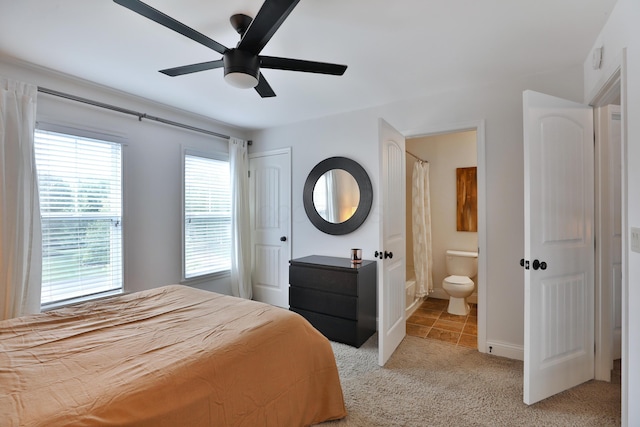 bedroom featuring light carpet, ensuite bathroom, and a ceiling fan