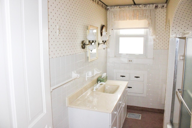 full bath with visible vents, tile walls, vanity, a wainscoted wall, and a shower with door