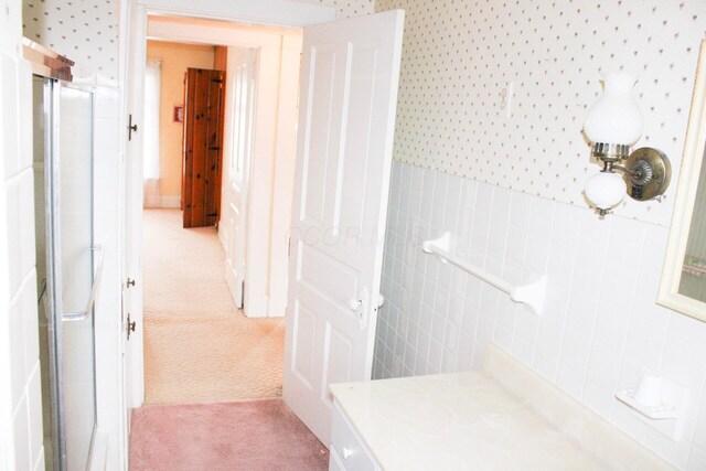 full bathroom featuring a stall shower, wallpapered walls, and wainscoting