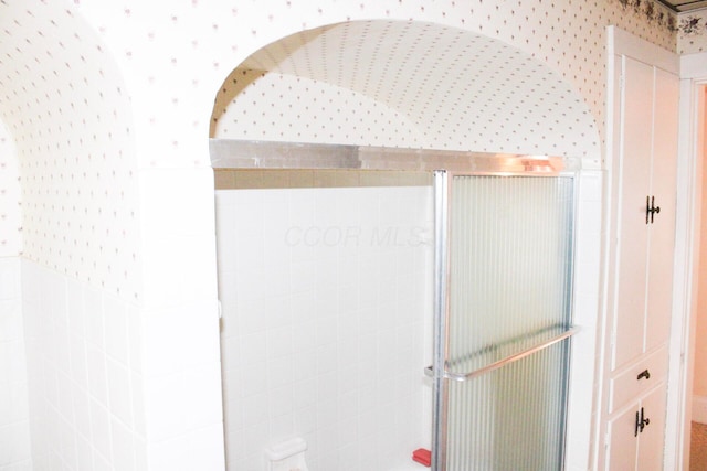 bathroom with a stall shower and wallpapered walls