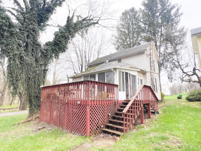 back of property featuring a deck and a lawn