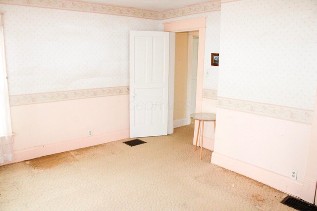 spare room featuring visible vents, light carpet, and wallpapered walls