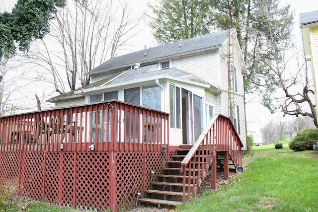 rear view of house featuring a yard, stairs, a wooden deck, and a shingled roof
