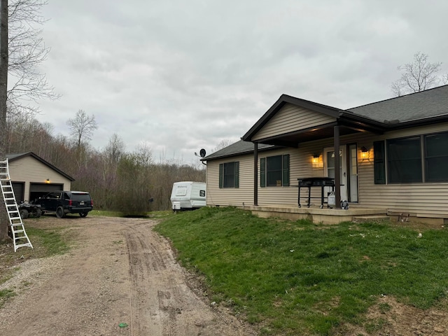 view of property exterior featuring covered porch, a lawn, and dirt driveway