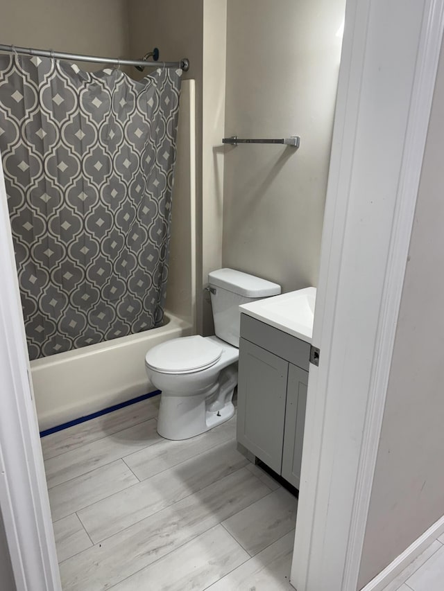 full bathroom with toilet, wood finished floors, shower / tub combo with curtain, and vanity