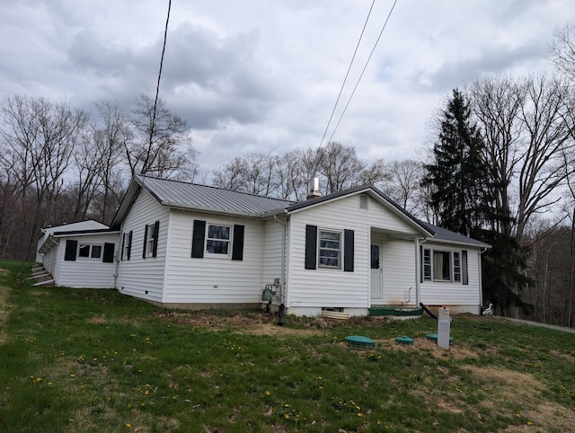 view of front facade with a front yard, metal roof, and a chimney