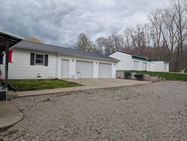 single story home with metal roof, a garage, and concrete driveway