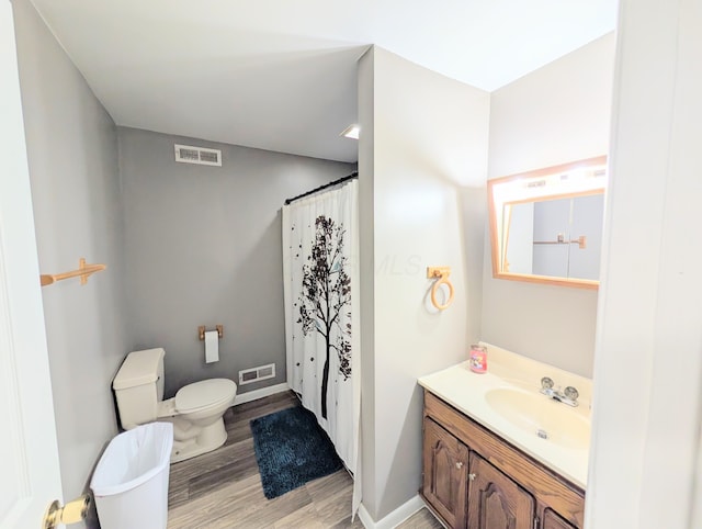 bathroom with toilet, wood finished floors, vanity, and visible vents