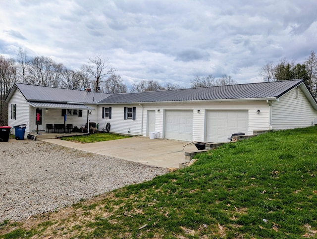 ranch-style home with an attached garage, metal roof, driveway, and a front lawn