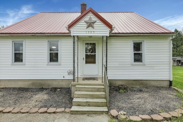 view of front of house featuring metal roof and a chimney