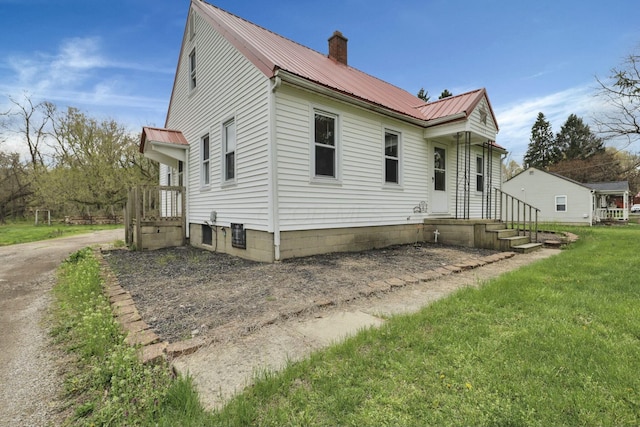 view of side of home featuring a yard, metal roof, and a chimney