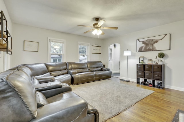 living area with ceiling fan, arched walkways, wood finished floors, and baseboards