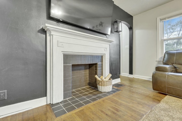 interior details with a fireplace with flush hearth, visible vents, baseboards, and wood finished floors