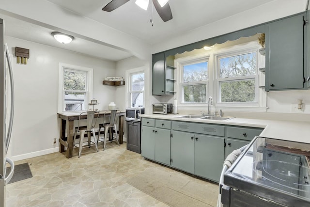 kitchen with ceiling fan, stone finish flooring, stainless steel microwave, a sink, and range with electric stovetop