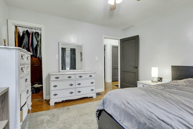 bedroom featuring a closet, wood finished floors, ceiling fan, and a spacious closet