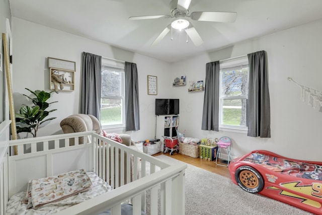 bedroom with multiple windows, wood finished floors, and a ceiling fan