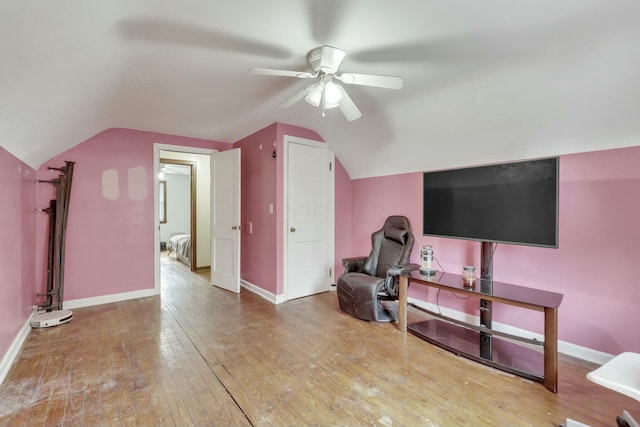 living area with ceiling fan, wood finished floors, baseboards, and lofted ceiling