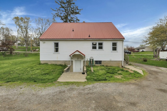 rear view of property featuring metal roof and a lawn