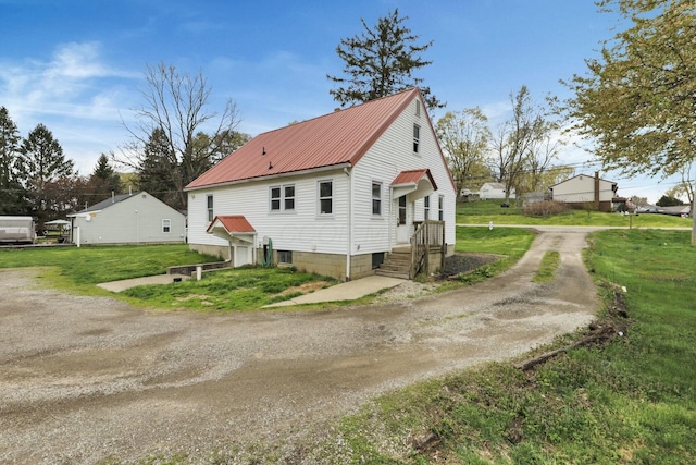 view of side of home with dirt driveway, metal roof, and a lawn