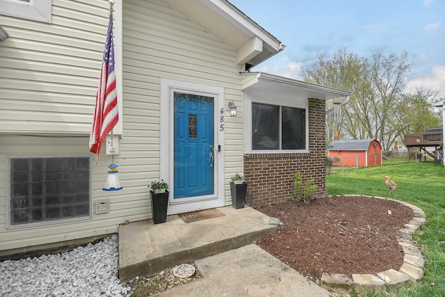 property entrance with brick siding and a lawn